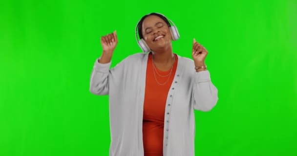 緑の画面上の黒人女性 音楽を聞きながらヘッドフォンやダンス 幸福と自由と楽しさ 女性は気楽で エンターテイメントとエネルギーで笑顔 モックアップスペースとラジオストリーミング — ストック動画