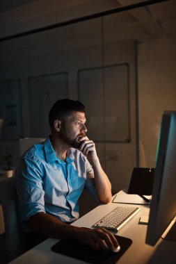 Başarının sırrı sıkı çalışmaktır. Yetişkin bir iş adamı geç saatlere kadar ofiste bilgisayar başında çalışıyor.