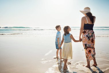 Güneşli yaz gününü bir aile olarak selamlıyorum. Sahilde iki küçük çocuğuyla kaynaşan bir annenin dikiz görüntüsü.