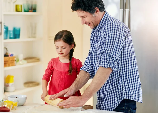 Its all about the technique. a middle aged father and his daughter preparing a pizza to go into the oven in the kitchen at home
