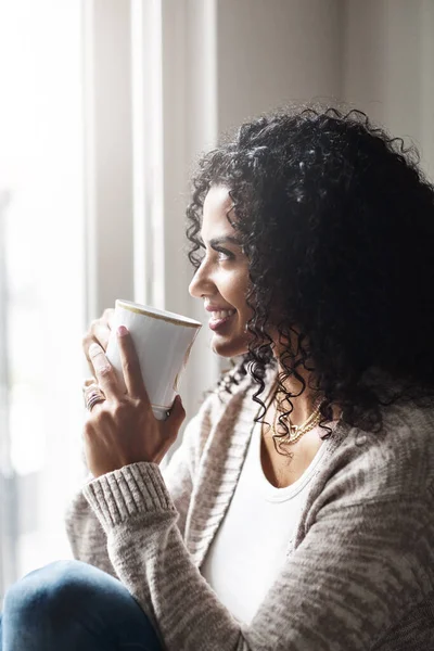 stock image How lucky I am to stay at home. a cheerful young woman enjoying a cup of coffee while being seated on a chair at home during the day