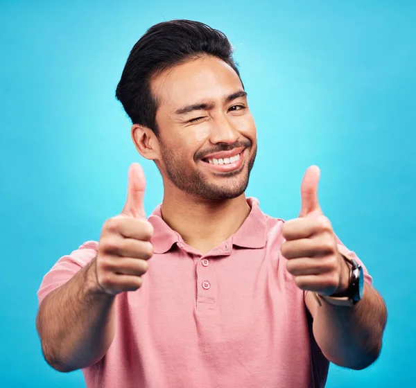 在工作室里 男人用正面的 反馈的或对蓝色背景的评论来刻画 竖起大拇指或眨眼 亚洲男模的脸 笑和手势 在孤立时表现出赞成 同意或投票的表情 — 图库照片