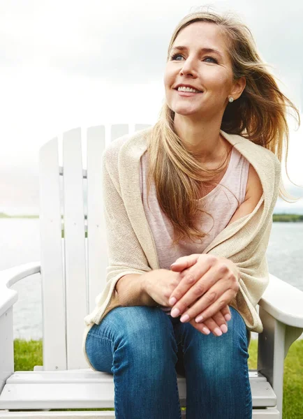 stock image Feeling the breeze of a blissful day. a mature woman sitting on a deck chair outside