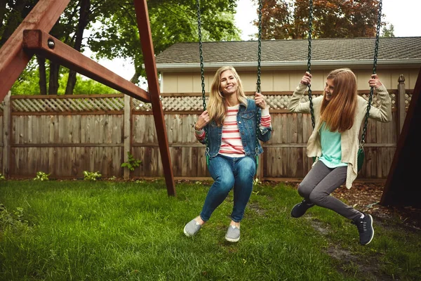 在我们自家后院玩得很开心一个母亲和她的女儿在自家后院荡秋千 — 图库照片