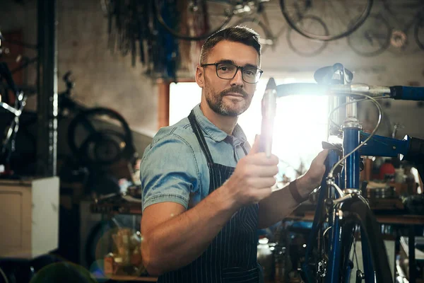 The bike doctor. Portrait of a mature man working in a bicycle repair shop