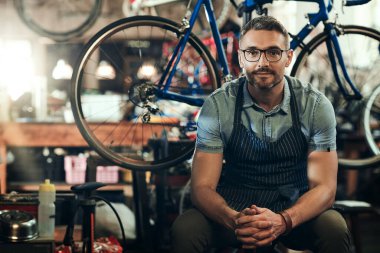 Motosikletlerinizi gönülden istiyorum. Bisiklet tamirhanesinde çalışan olgun bir adamın portresi.