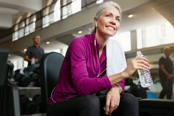 Happiness is important for great health. Portrait of a happy senior woman holding a water bottle and taking a break from her workout at the gym