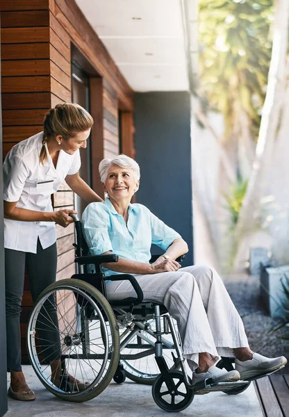 患者さんのニーズをすべて満たしていることを確認します 老人ホームの外の車椅子で介護する看護師 — ストック写真