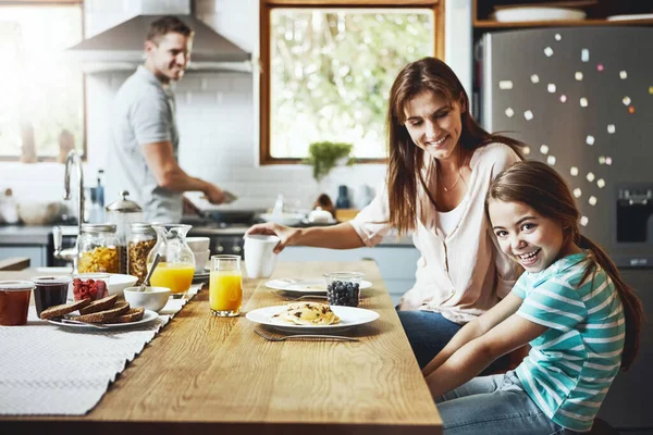 得给我们的肚子添些好吃的一个小女孩在家里和父母一起吃早餐的画像 — 图库照片