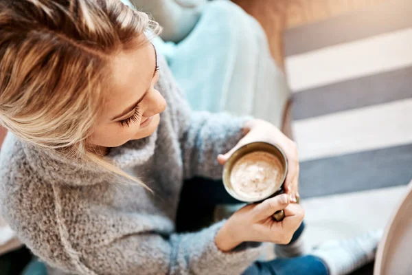 stock image Taking it slow today. a young woman relaxing on the sofa at home with a warm beverage