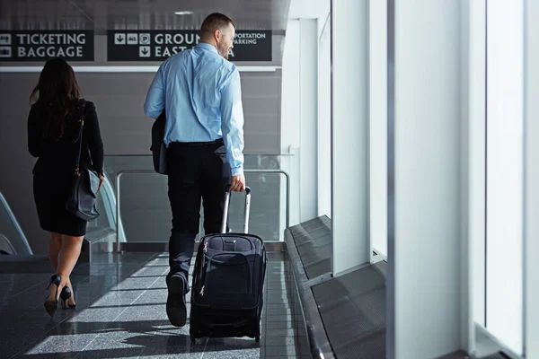 Success is a journey they know well. two executive businesspeople walking through an airport during a business trip