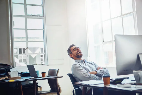 stock image Laughter is a great way to lighten up the workday. a mature businessman laughing while working on a computer in an office