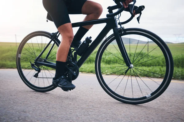 Closeup, legs and athlete on bicycle outdoor for exercise, training and triathlon sports. Person, bike and cycling on road for freedom, cardio fitness and performance with speed, power and transport.