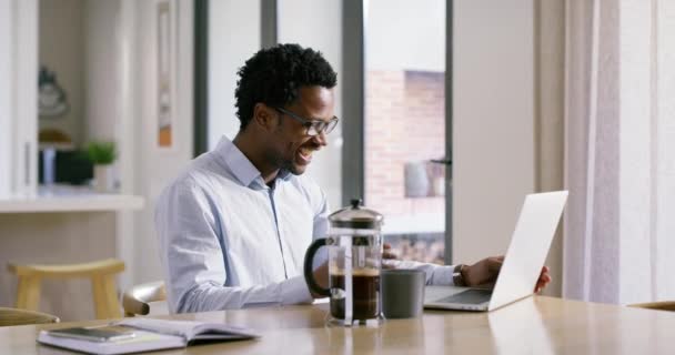自宅でノートパソコンを持つビデオ通話 黒人男性は笑い 波とビデオ会議で笑顔 コーヒーとリビングルームでコンピュータ上で働くコミュニケーション オンライン会議やビジネスマン — ストック動画