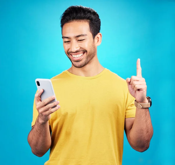 アジアの男性 男性は 青いスタジオの背景に対するアイデア 解決策 または質問を指摘します 幸せな人や携帯電話 インターネットやウェブサイト上のユーザーとモックアップで解決するためのポイント — ストック写真