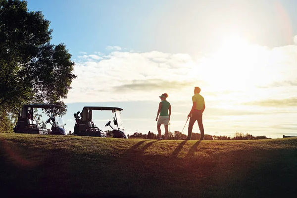 昼はゴルファー 夜は夫と妻 フェアウェイにあるゴルフカートに戻ると — ストック写真