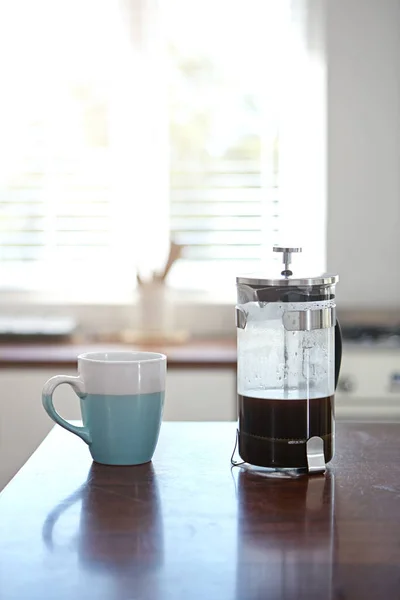 Its a morning necessity. a mug and french press on a kitchen counter