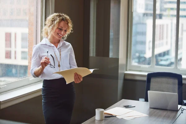 stock image Profit is proof of her career commitment. a businesswoman reading a report in an office