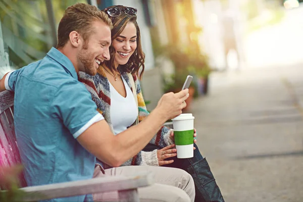 他是来击败她的高分的 一对快乐的年轻夫妇一起用智能手机在市中心度过一天 — 图库照片