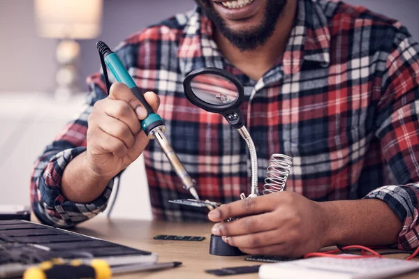 Man, electrician hands with soldering iron to fix computer hardware, magnifying glass and tech repair. Maintenance, tools and technician fixing electrical problem with male working on device.