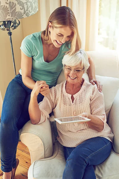 stock image Bonding with mom in the internet age. a woman showing her elderly mother how to use a tablet at home