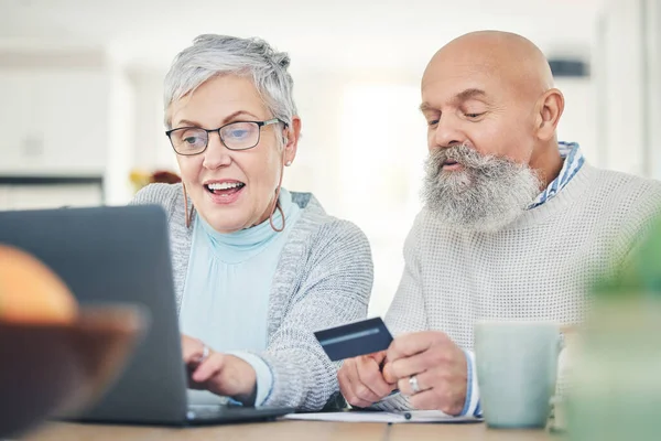 stock image Laptop, senior couple and credit card in home for online shopping, digital banking or payment. Computer, ecommerce and happiness of man and woman on internet for sales, retirement finance or fintech