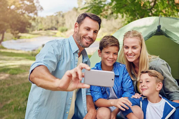 Smile everyone. a family of four taking a selfie while camping