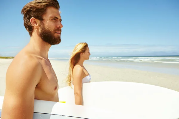 サーフィンについての深刻な ビーチを歩いている若いカップルがサーフボードを持っていて — ストック写真