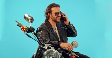 Telefon görüşmesi, motosiklet ve mavi arka plandaki stüdyoda motosikletçi estetiği için özgürlük ve eğlence. Akıllı telefon, sohbet ve motosikletli adam sürücü tatil, yolculuk ya da binicilik için.