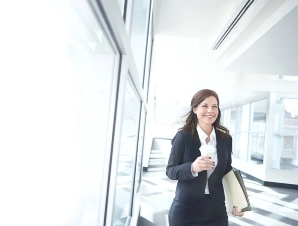 ファイルとコーヒーカップを持って廊下を歩いているビジネスマンの女性 彼女の職場で幸せな美しい女性幹部 ビジネスの人は成功の準備ができて笑顔 働きやすい起業家 — ストック写真