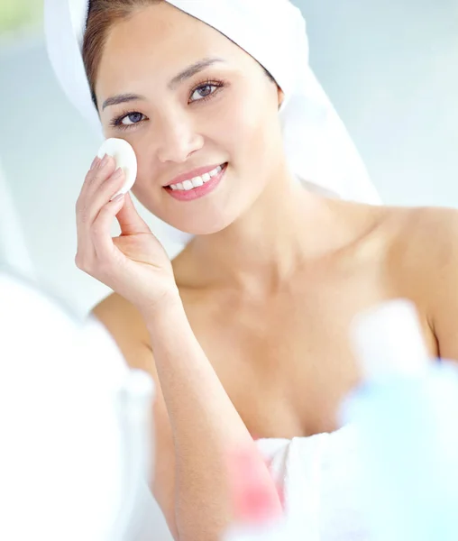 stock image Sticking to her beauty routine. An attactive young Asian woman applying moisturizer with a towel on her head