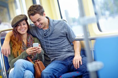Sosyal medyayı birlikte paylaşıyoruz. Mutlu bir çift trende otururken cep telefonlarına bakıyor.