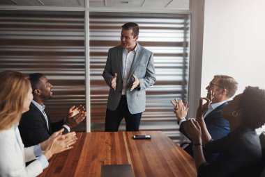 Büyük liderler güçlerini başkalarını güçlendirmek için kullanır. Bir grup iş adamı bir ofiste meslektaşlarını alkışlıyor.