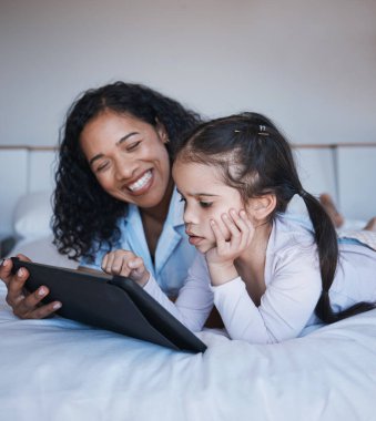 Tablet, anne ve kız yatak odasında, sosyal medyada ya da internette rahatlıyor. Teknoloji, mutluluk ve öğrenim, film ya da video için dokunmatik ekranı olan anne ve çocuk.