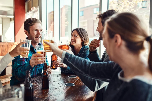stock image Having a pint at the bar with friends. a group of friends making a toast while enjoying themselves in a bar