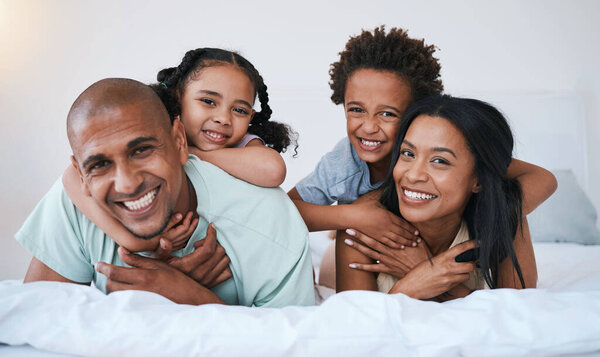 Portrait, family and smile in home bedroom, bonding and relaxing or lying together. Bed, happiness and children with mother and father or parents enjoying quality time, having fun and care in house