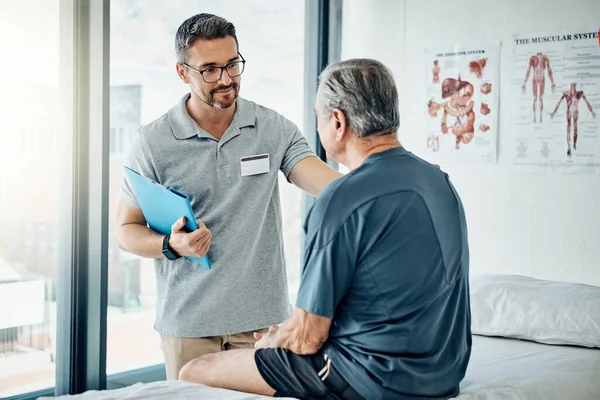 stock image You dont have to live in pain. a caring physiotherapist consulting with his mature patient in the rehabilitation center
