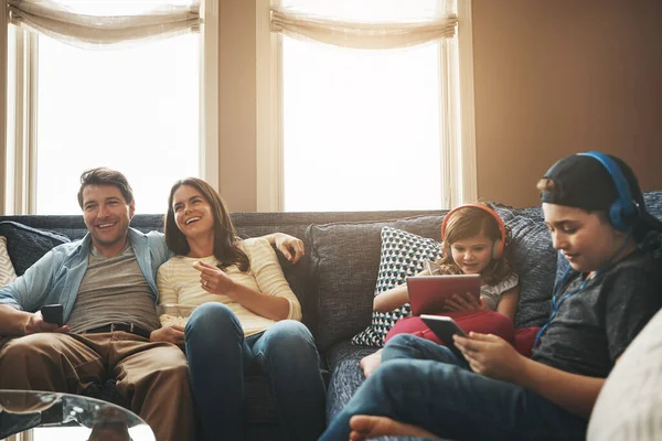 整个周末都在娱乐 一对夫妇一边看电视 一边让他们的孩子忙着在家里用数码平板电脑 — 图库照片