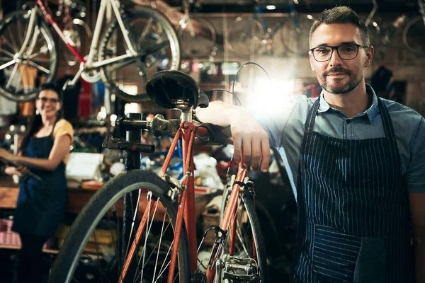 我会把你的自行车弄得和新的一样好 一个成熟男人和他的同事在自行车修理店工作的肖像 — 图库照片