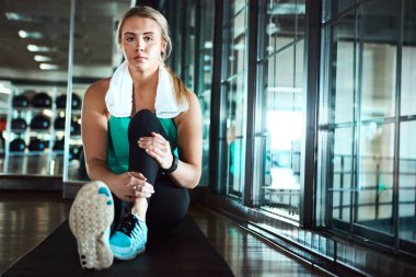 Isınıyorum. Çekici bir genç kadın spor salonunda ısınma rutinini yaşıyor.