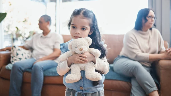 Divorce, mother and father with a sad girl, teddy bear and separation at home, living room and ignore. Parents, mama and dad with daughter, female child with a toy and family with issues and problems.