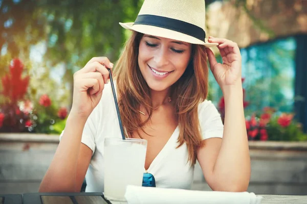 帽子を持ってきてよかった 帽子をかぶって外のレストランに座って冷たい飲み物を楽しんでいる陽気な若い女性 — ストック写真