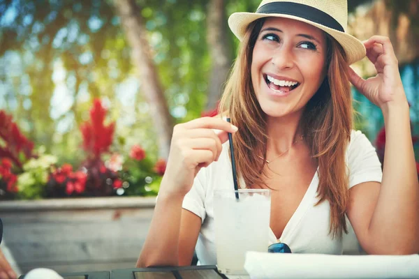 次に何をしたいですか 帽子をかぶって外のレストランに座って冷たい飲み物を楽しんでいる陽気な若い女性 — ストック写真