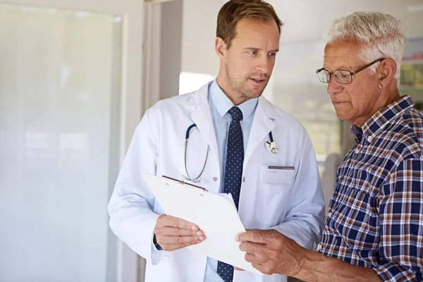 Lets go over a couple of things. a male doctor talking to a senior patient in the retirement home