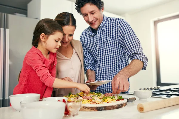 为最后的触摸 一家人一起准备比萨饼 准备在家里厨房里的烤箱里吃 — 图库照片