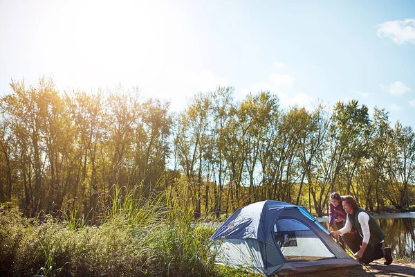 Stock image Home is where your tent is. an adventurous setting up their tent by the lake