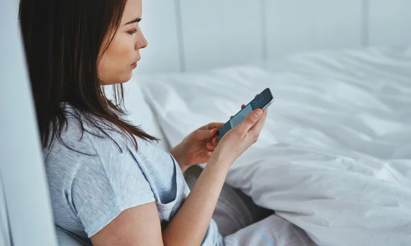 Mesajlarını Kontrol Ediyorum Çekici Bir Genç Kadının Yatakta Yatarken Mesajlarını — Stok fotoğraf