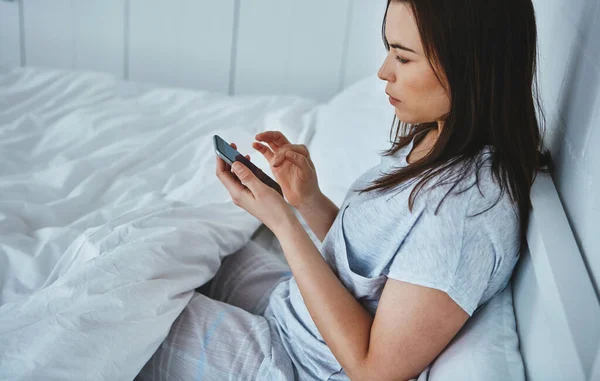 Bir Mesajla Uyanmak Çekici Bir Genç Kadının Yatakta Yatarken Mesajlarını — Stok fotoğraf