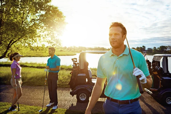 Lets get golfing. a man playing a round of golf with his friends