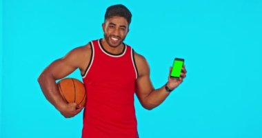 Basketbol, telefon ve yeşil ekran. Stüdyoda spor pazarlaması için mavi arka planda bir adam var. Mobil ekranda veya ekranda krom anahtarı gösteren bir erkek sporcuyla portre, egzersiz ve eğitim.